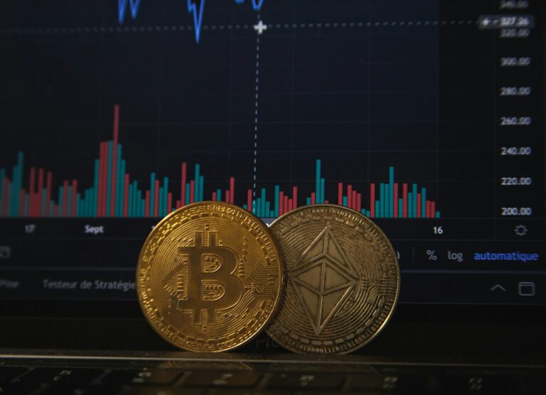 Bitcoin and Ethereum coins on a laptop keyboard with a trading chart